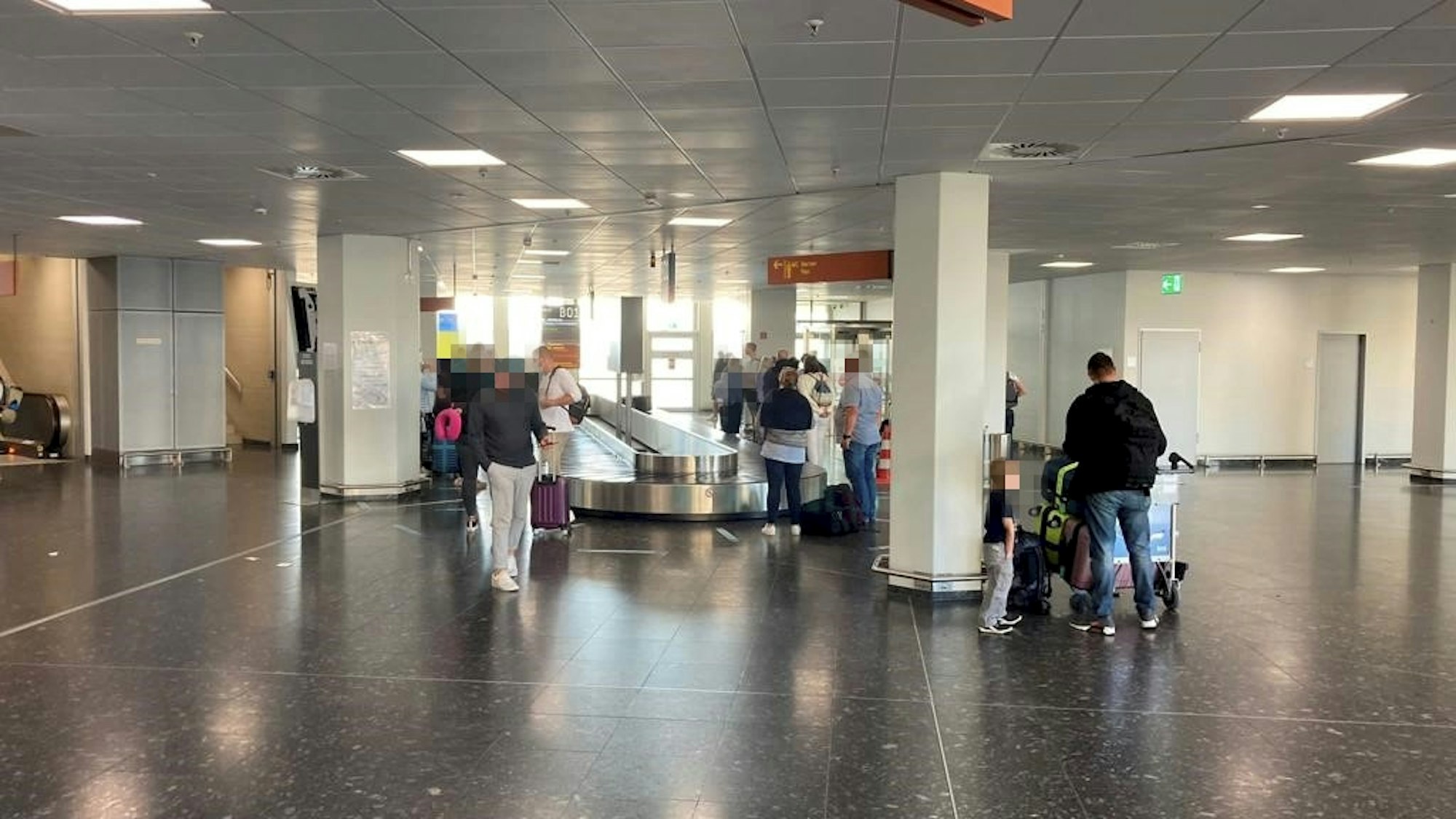 Menschen stehen an einem Gepäckband im Köln-Bonner Flughafen