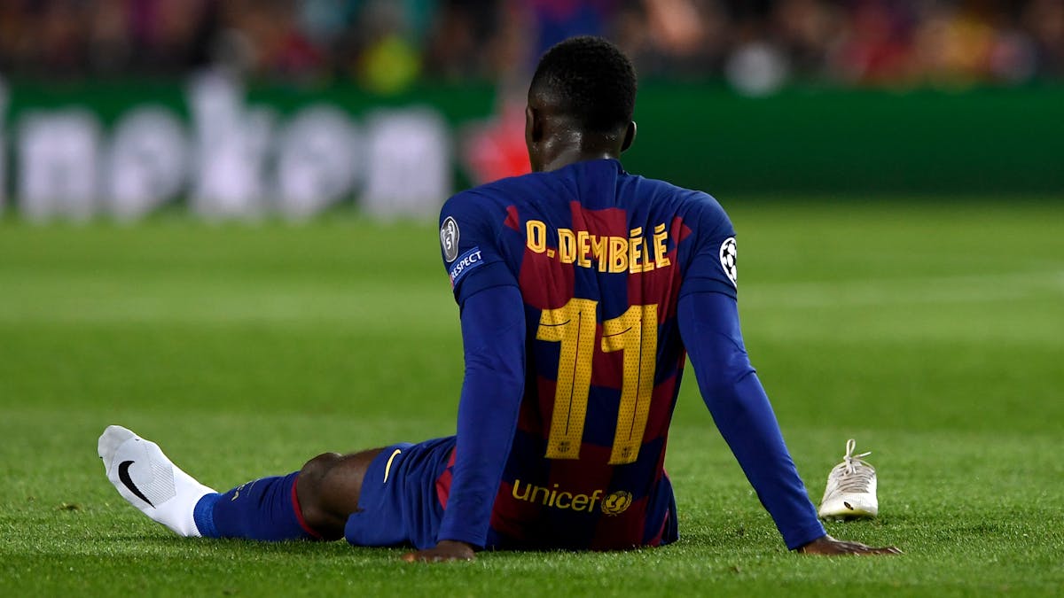 Ousmane Dembélé sitzt bei einem Spiel des FC Barcelona nach einer Verletzung auf dem Rasen des Camp Nou.