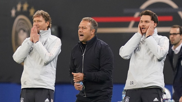 Bundestrainer Hansi Flick (M) sowie die Assistenztrainer Marcus Sorg (l) und Danny Röhl agieren an der Seitenlinie.