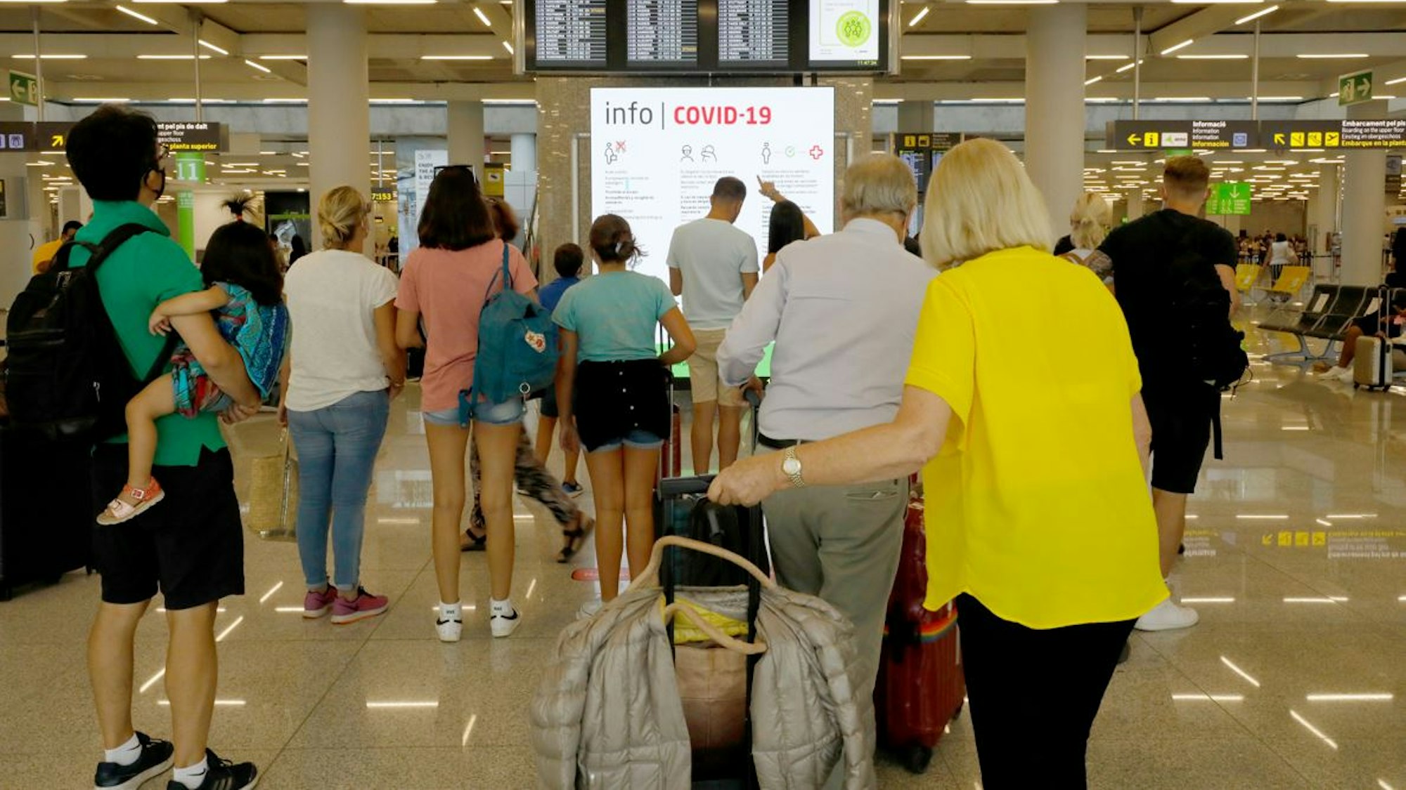 Menschen informieren sich am 1. August 2021 im Abflugbereich des Flughafens von Palma de Mallorca über Corona-Regeln. Für die Herbstferien wurden zwei getrennte Schlangen für geimpfte und ungeimpfte Reisende eingerichtet.