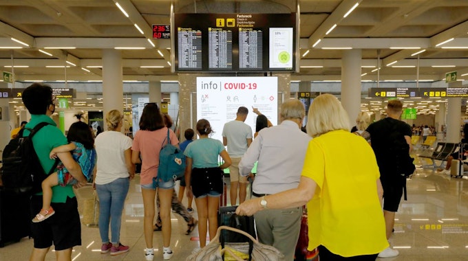 Menschen informieren sich am 1. August 2021 im Abflugbereich des Flughafens von Palma de Mallorca über Corona-Regeln. Für die Herbstferien wurden zwei getrennte Schlangen für geimpfte und ungeimpfte Reisende eingerichtet.