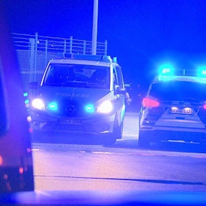 Polizisten passieren in Polizeifahrzeugen ein Tor am Flughafen Weeze, wo ein Auto einen Zaun an einer Rollbahn durchbrochen hat.