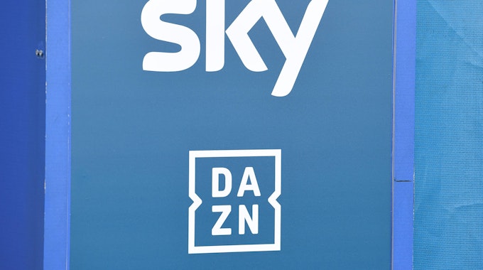 Die Logos der TV-Anbieter Sky und DAZN sind auf eine Tafel gedruckt.