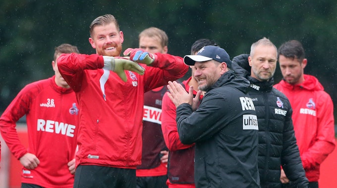 Torwart Timo Horn und Trainer Steffen Baumgart lachen während des Trainings gemeinsam.