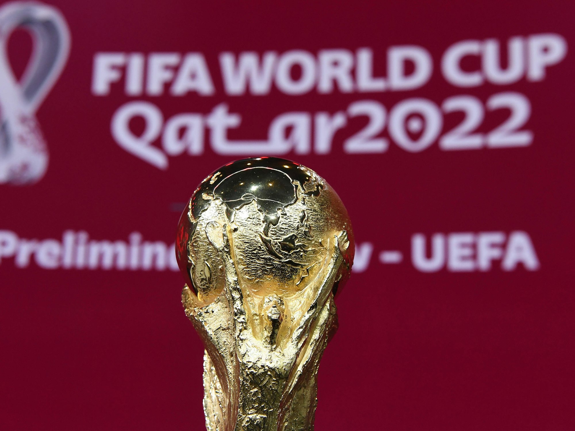 WM-Pokal vor einem Banner der WM 2022 in Katar bei der UEFA-Vorrundenauslosung
