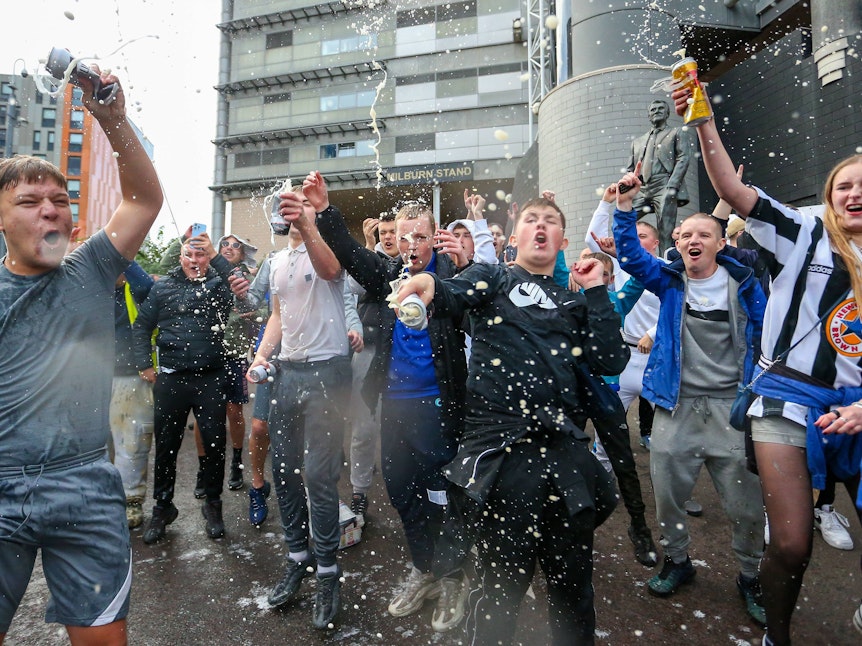 Jugendliche Newcastle-Fans tanzen spritzen mit Bierdosen um sich.
