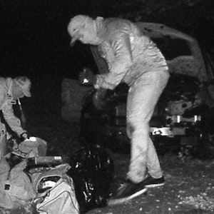 Auf dem Bild der Wildkamera sieht man, wie Unbekannte bei Nacht Einzelteile des ausgeschlachteten BMW in Taschen verstauen.