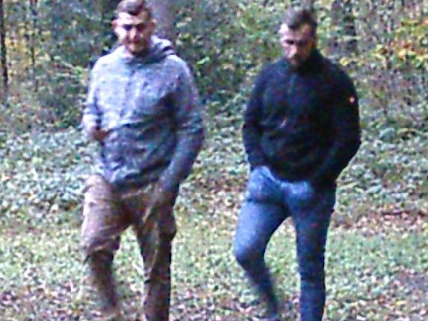 Zwei Männer stapfen bei Tag durch den Wald. Das Foto wurde ebenfalls von der Wildkamera aufgenommen.