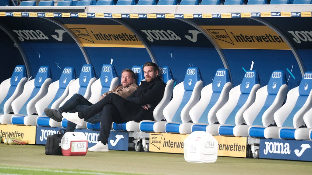 Thomas Kessler und Jörg Jakobs sitzen bei der Partie TSG Hoffenheim gegen 1. FC Köln auf der Bank.