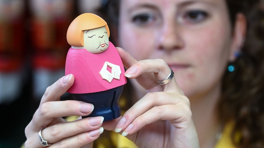 Bundeskanzlerin Merkel gibt es auch als Räucherfigur. Auf dem Foto sieht man Künstlerin Sina Klement, die solche eine Räucherfigur in der Hand hält.