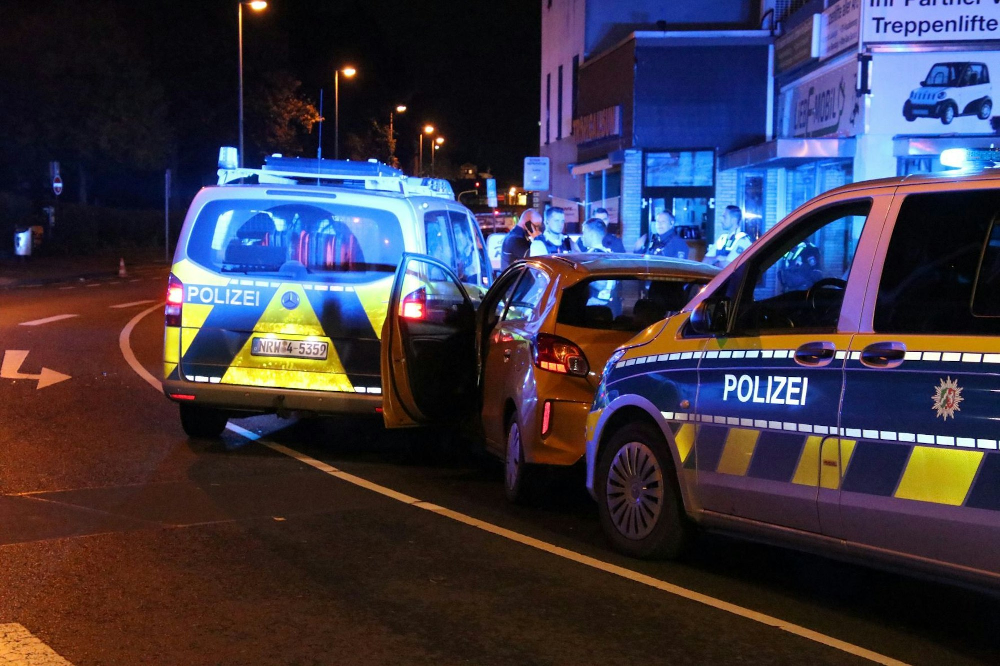 Zwei Polizeifahrzeuge stehen vor beziehungsweise hinter einem Auto.