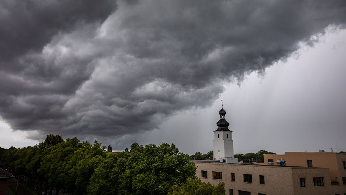 Dunkle Wolken ziehen am 4. Juli 2021 kurz vor einem Gewitter mit Starkregen über den Kölner Ortsteil Sülz. Der Kirchturm rechts gehört zur Kirche „Zur heiligen Familie“.&nbsp;