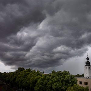 Dunkle Wolken ziehen am 4. Juli 2021 kurz vor einem Gewitter mit Starkregen über den Kölner Ortsteil Sülz. Der Kirchturm rechts gehört zur Kirche „Zur heiligen Familie“.
