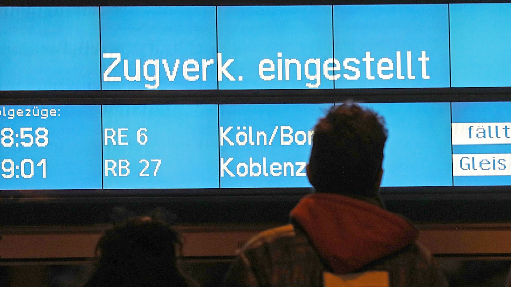 Zugreisende blicken am 10. März 2019 in Köln auf eine Anzeigetafel mit dem Hinweis "Zugverkehr eingestellt". Mit Orkanböen bis Windstärke 12 hat das Sturmtief «Eberhard» den Bahnverkehr in Teilen Deutschlands zum Erliegen gebracht.