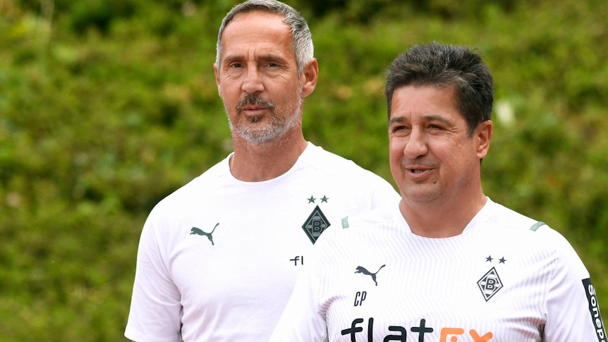 Adi Hütter (l.), Cheftrainer von Fußball-Bundesligist Borussia Mönchengladbach, und sein Co-Trainer Christian Peintinger (r.) am 10. Juli 2021 beim Testspiel der Fohlen gegen Viktoria Köln im Rheydter Grenzlandstadion. Beide Trainer lächeln.