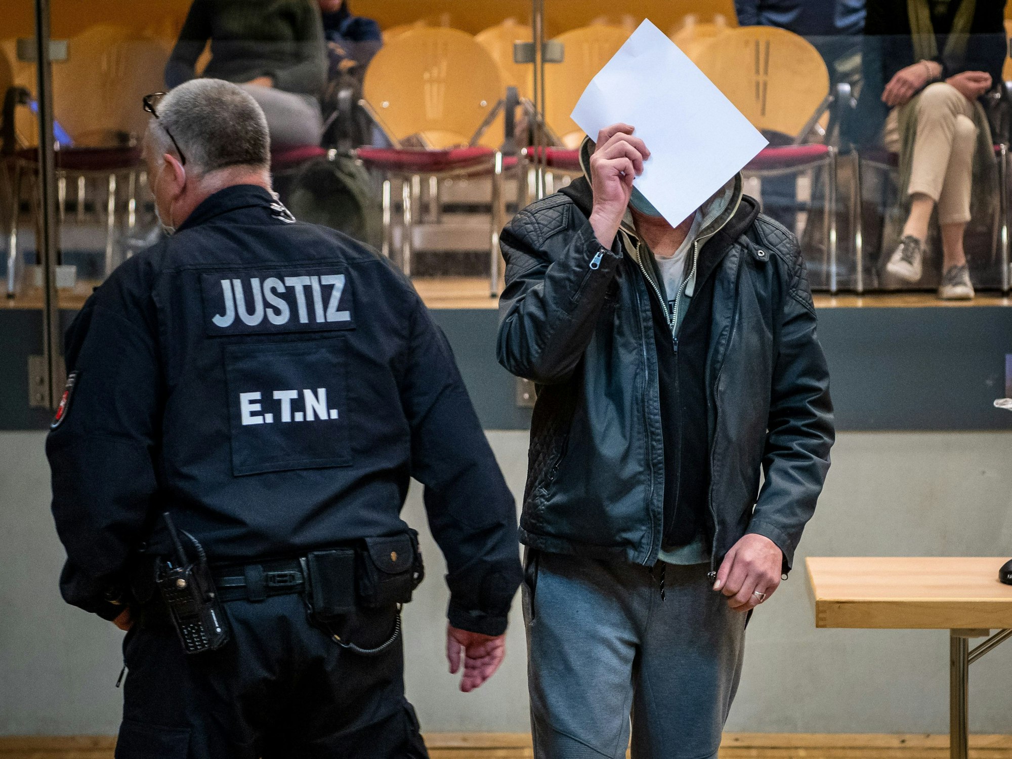 Ein Angeklagter (hier ein Foto vom 18.10.2021) im Mordprozess wird in die Stadthalle geführt. Nach dem Tod einer gefesselten 19-Jährigen in der Weser im niedersächsischen Kreis Nienburg stehen zwei Männer und eine Frau seit Februar wegen Mordes vor Gericht.