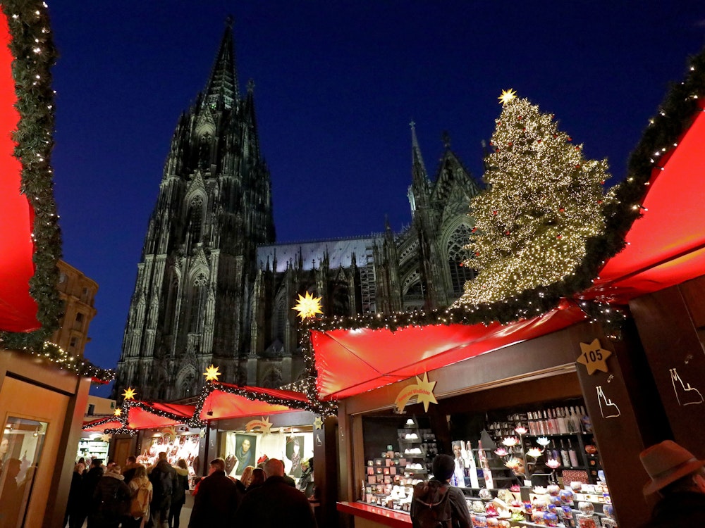 Besucher gehen über den Weihnachtsmarkt vor dem Kölner Dom.
