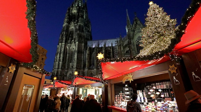 Besucher gehen über den Weihnachtsmarkt vor dem Kölner Dom.