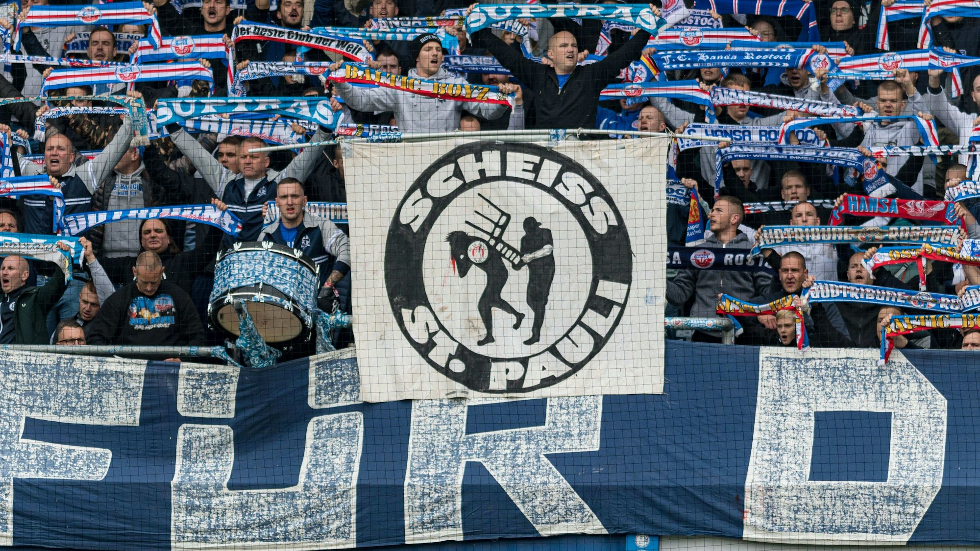 Fans von Hansa Rostock halten ein Banner gegen den FC St. Pauli hoch.