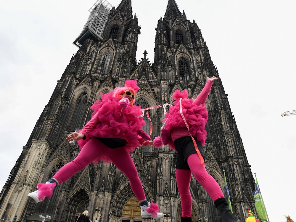 Verkleidete Frauen springen vor dem Kölner Dom in die Höhe. Die Weiberfastnacht leitet den Beginn des Straßenkarnevals ein. +++ dpa-Bildfunk +++