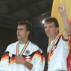 Der deutsche Mittelfeldspieler und Kapitän Lothar Matthäus (r) und sein Mitstreiter Pierre Littbarski (l) bejubeln vor der deutschen Fahne den WM-Titel.