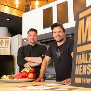 Tim Mälzer und Steffen Henssler stehen im Studio der neuen Kochshow „Mälzer und Henssler liefern ab!“ bei Vox
