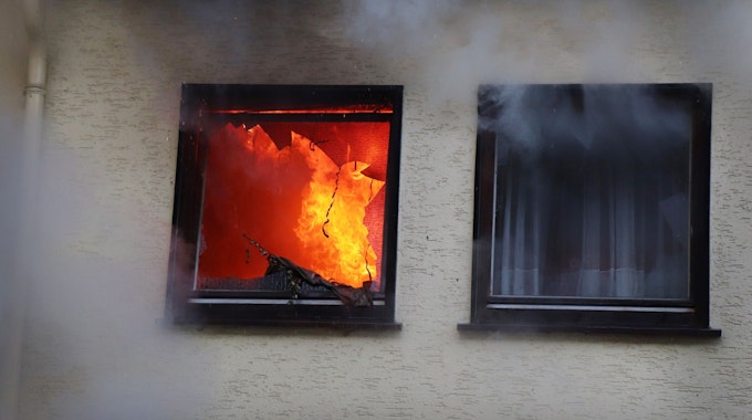 Hinter einem Fenster eines Hauses in Dortmund sind am 9. Januar 2019 Flammen zu sehen.