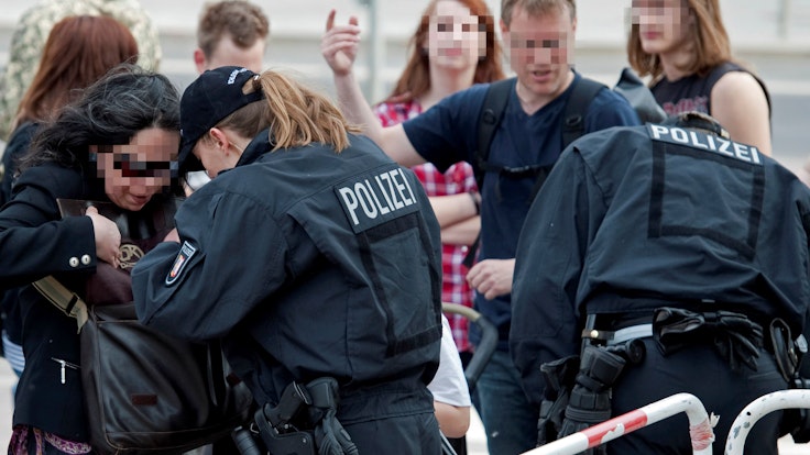 Eine Polizisten führt am Mauerpark in Berlin eine Taschenkontrolle durch.