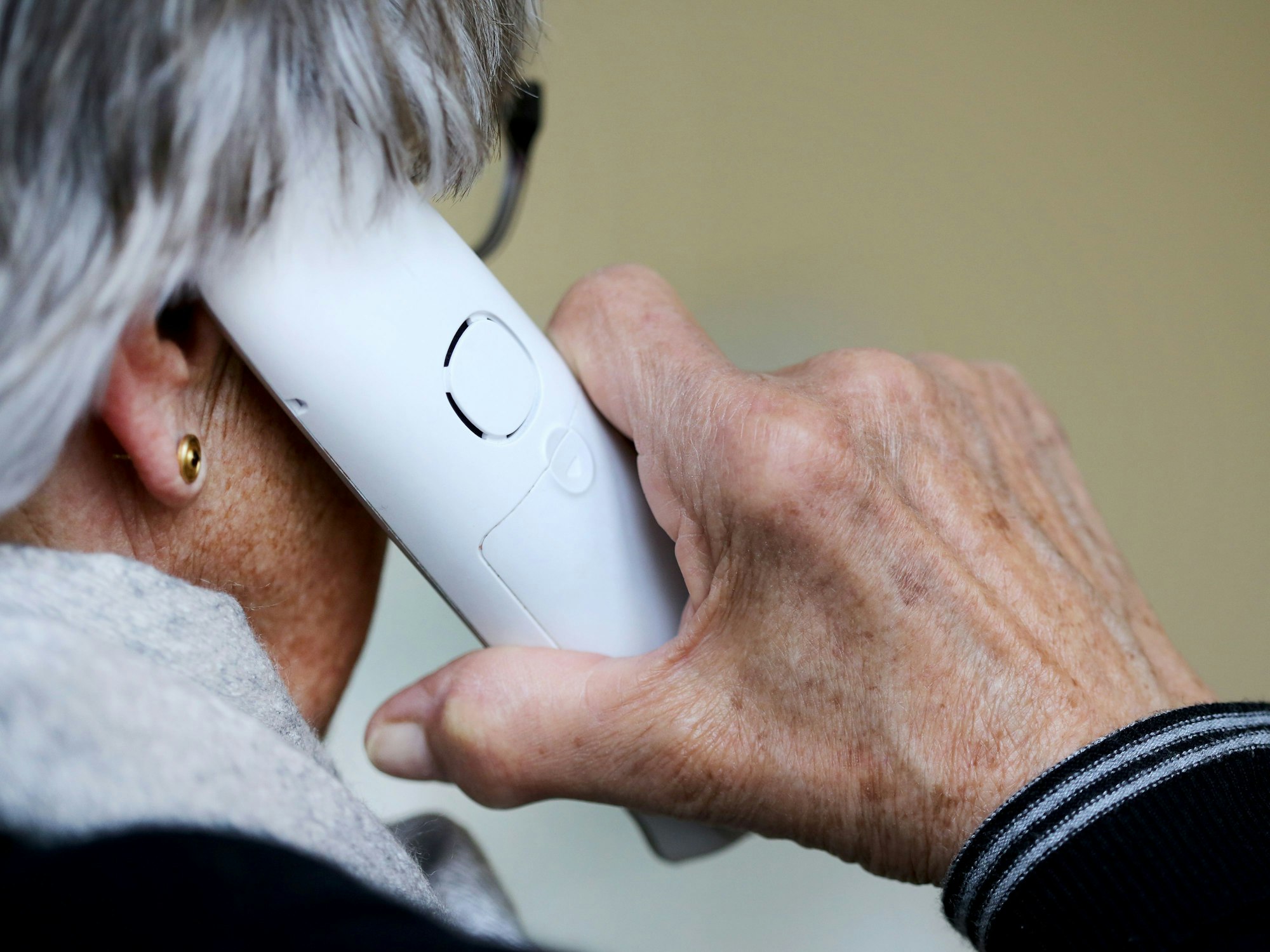 Das Symbolfoto (aufgenommen am 10. März 2021) zeigt eine ältere Dame, die in ihrer Wohnung ein Telefongespräch annimmt.