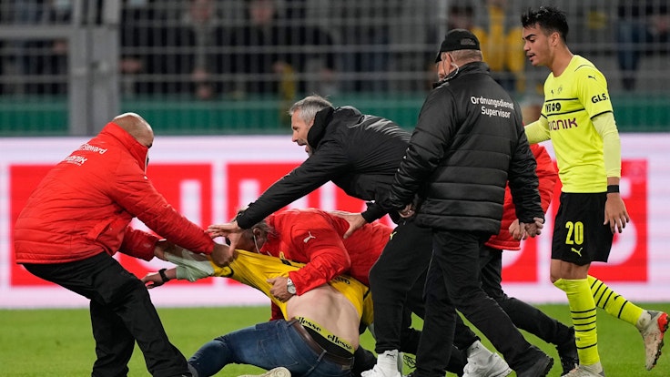 BVB-Trainer Marco Rose versucht zwischen den Ordnern und dem Flitzer zu schlichten.