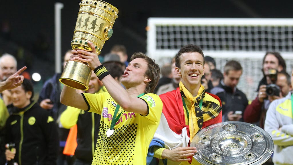 Damaliger Spieler Kevin Großkreutz von Borussia Dortmund jubelt am 12.05.2012 mit dem DFB-Pokal neben seinem Teamkollegen Ivan Perisic mit Meisterschale nach dem gewonnen DFB-Pokal-Finale zwischen Borussia Dortmund und Bayern München in Berlin.