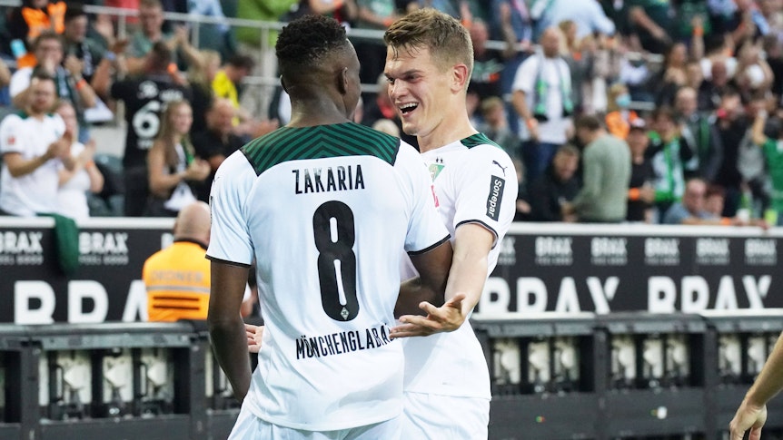 Denis Zakaria (l.) und Matthias Ginter (r.), beide noch bis Ende Juni 2022 bei Fußball-Bundesligist Borussia Mönchengladbach unter Vertrag, freuen sich gemeinsam über den Siegtreffer im Duell gegen Dortmund am 25. September 2021. Beide schauen sich an und lachen.