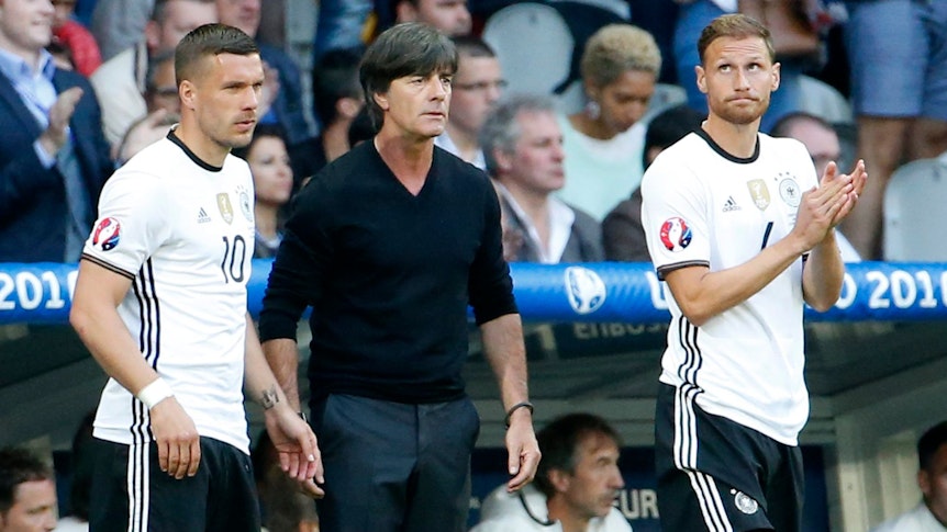 Benedikt Höwedes, Joachim Löw und Lukas Podolski stehen bei einem Deutschland-Spiel nebeneinander.