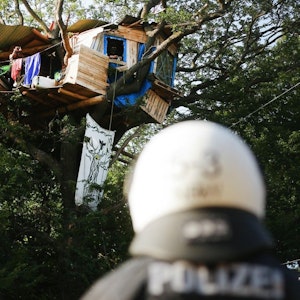 Am 23.06.2020 stehen zwei Polizisten am Fuße eines Baumes, in dem Aktivisten ein Haus im Hambacher Forst gebaut haben.