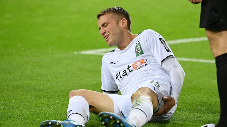 Jordan Beyer von Borussia Mönchengladbach, hier am 27. Oktober 2021, liegt auf dem Boden und hält sich den hinteren Oberschenkel mit schmerzverzerrtem Gesicht.