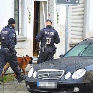 Mönchengladbach: Polizisten und ein Spürhund stehen vor einem Haus.