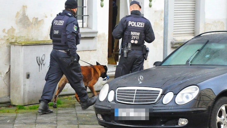 Mönchengladbach: Polizisten und ein Spürhund stehen vor einem Haus.