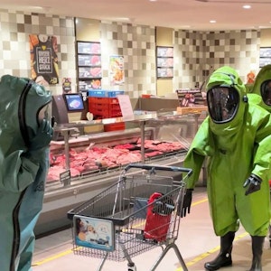 Einsatzkräfte laufen mit Chemikalienschutzanzügen durch einen Supermarkt.