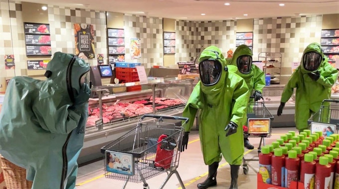 Einsatzkräfte laufen mit Chemikalienschutzanzügen durch einen Supermarkt.