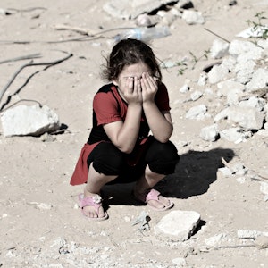 Das Symbolfoto (aufgenommen am 14. September 2014) zeigt ein Mädchen in den Ruinen von Shejaiya. Sie kauert auf dem Boden und hält sich die Hände vors Gesicht.