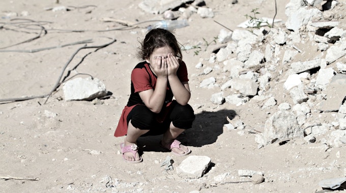 Das Symbolfoto (aufgenommen am 14. September 2014) zeigt ein Mädchen in den Ruinen von Shejaiya. Sie kauert auf dem Boden und hält sich die Hände vors Gesicht.