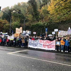 Schülerinnen und Schüler des Gymnasiums Nonnenwerth stehen an einer Straße und demonstrieren für den Erhalt ihrer Schule.