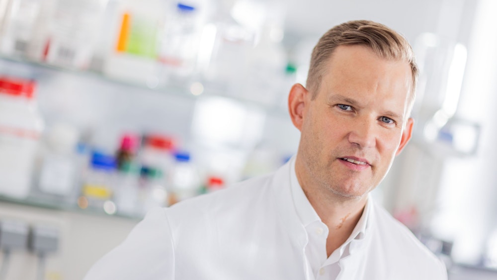 Hendrik Streeck, Direktor des Instituts für Virologie an der Uniklinik Bonn, steht mit einem weißen Kittel in einem Labor seines Institutes.