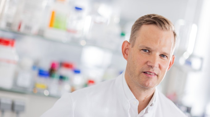 Hendrik Streeck, Direktor des Instituts für Virologie an der Uniklinik Bonn, steht mit einem weißen Kittel in einem Labor seines Institutes.