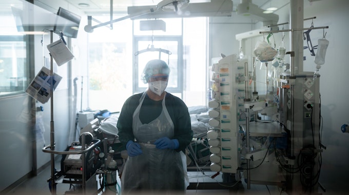 Eine Mitarbeiterin der Pflege steht in einem Patientenzimmer der Corona-Intensivstation des Universitätsklinikums Essen.
