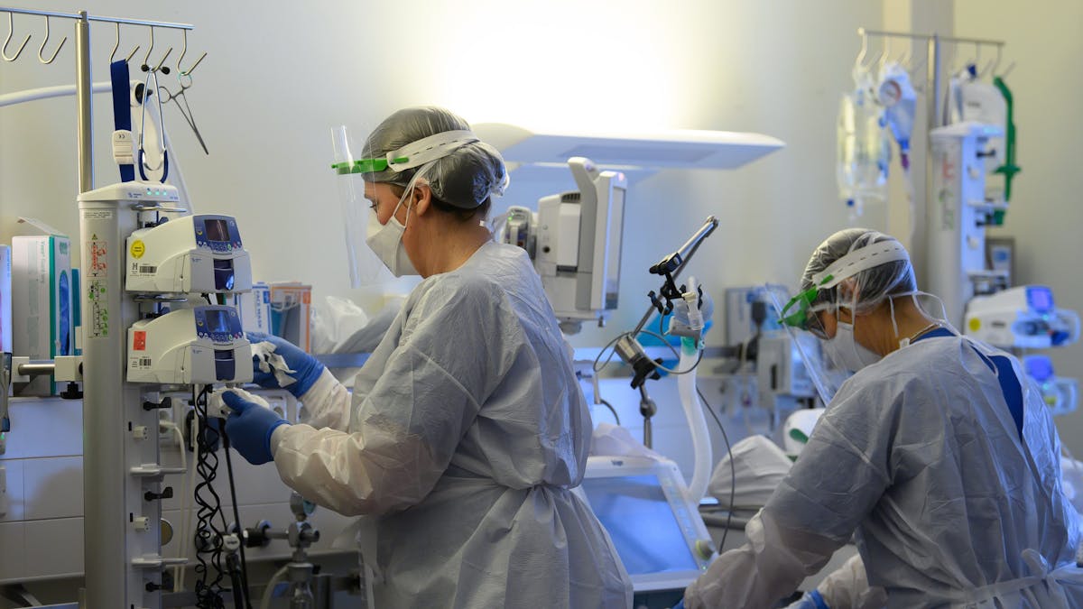 Intensivpflegerinnen sind in Schutzkleidungen auf der Covid-19-Intensivstation einer Klinik mit der Versorgung von Corona-Patienten beschäftigt.