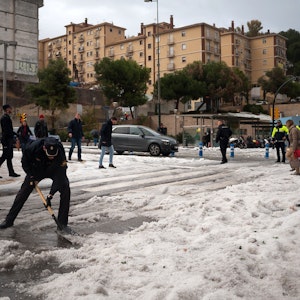 Ein Polizist räumt nach einem schweren Hagelsturm in der Innenstadt von Malaga den Hagel von der Straße. Das Sturmtief «Gloria» hat in Spanien große Schäden hinterlassen.