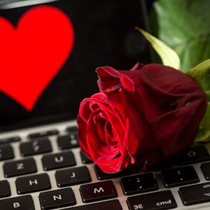 Online-Dating generell ist nicht einfach, doch vor allem gläubige Menschen haben Schwierigkeiten dabei, einen Partner zu finden. Extra Dating-Apps sollen dabei helfen. Das Symbolfoto (aufgenommen am 20. April 2016) zeigt eine Rose, die auf einer Computertastatur liegt. Im Hintergrund ist ein Smartphone zu sehen, auf dem ein Herz abgebildet ist.