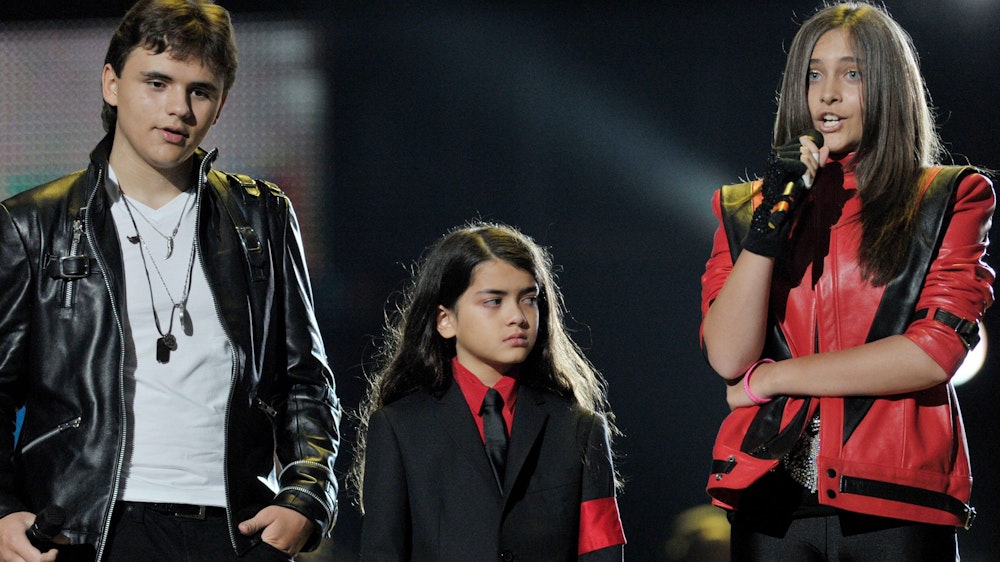 Blanket Jackson steht in einem schwarzen Anzug und einem roten Hemd mit seinen Geschwistern Prince (l.) und Paris (r.) am 08. Oktober 2011 auf einer Bühne.