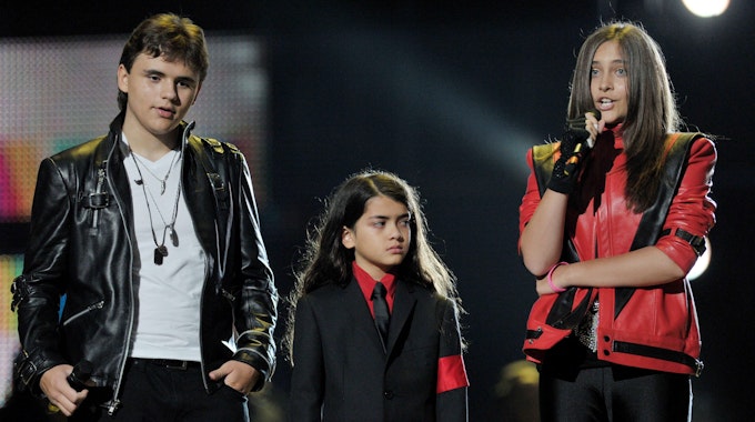 Blanket Jackson steht in einem schwarzen Anzug und einem roten Hemd mit seinen Geschwistern Prince (l.) und Paris (r.) am 08. Oktober 2011 auf einer Bühne.